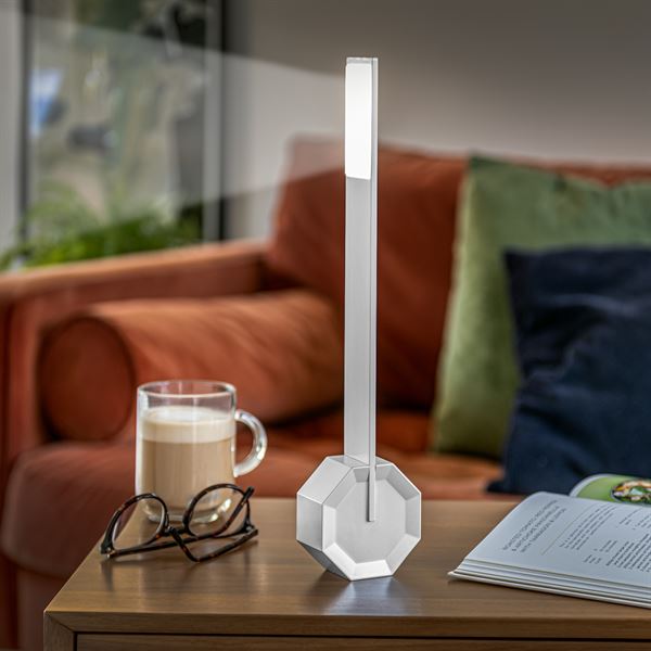 Gingko Octagon one desk lamp in Silver Aluminium upright on a coffee table