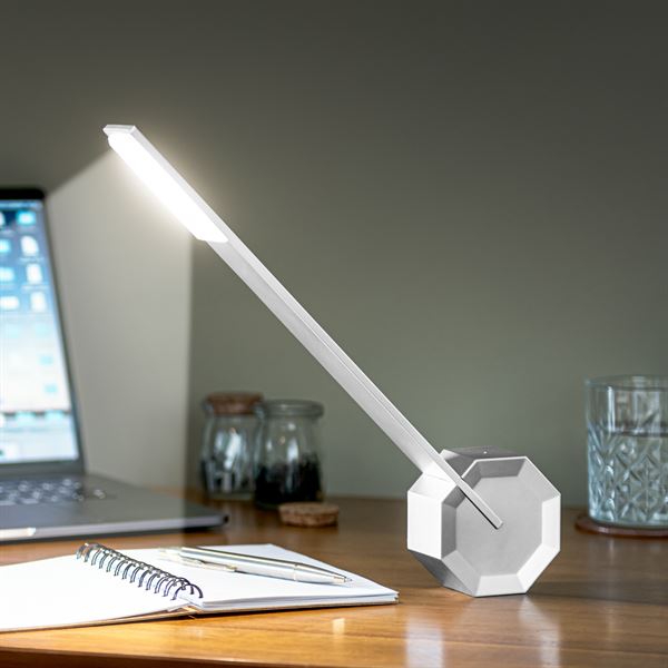 Gingko Octagon one desk lamp in Silver Aluminium on a desk lighting up a book