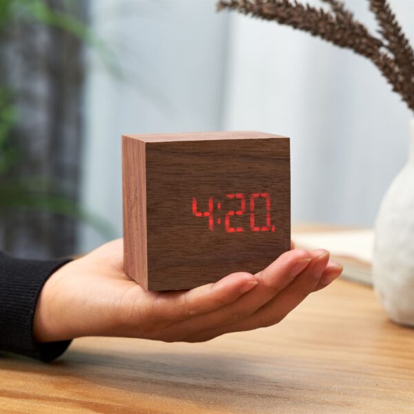 Gingko Cube plus clock in sustainable walnut wood held in a hand