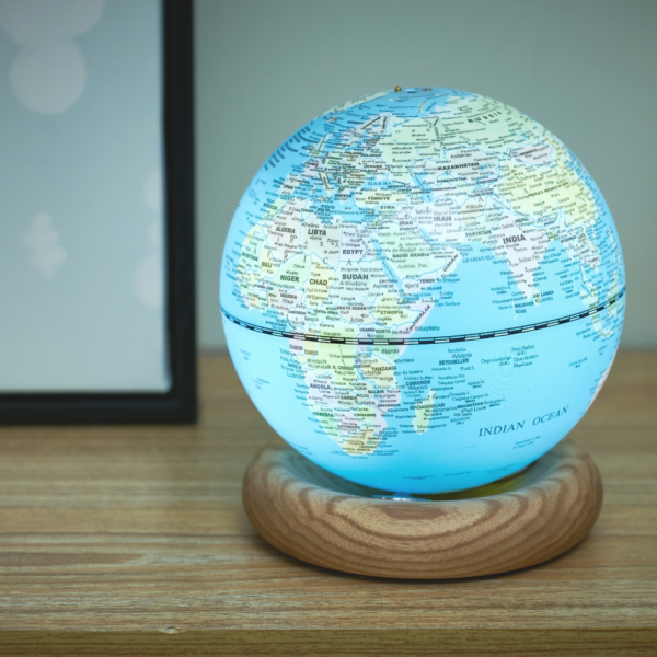 Gingko Mini Light Blue Atlas Globe with White Ash Base displayed on a shelf