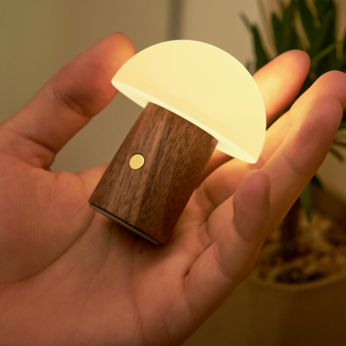 Walnut mini Alice mushroom light held in palm of a hand